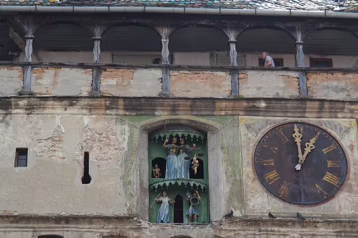Clock tower facade with ornate figurines and Roman numeral clock face in Sighisoara, Romania