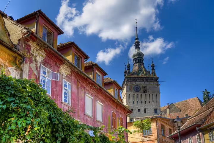 Colorful medieval buildings and Clock Tower in Sighisoara fortress citadel under blue sky