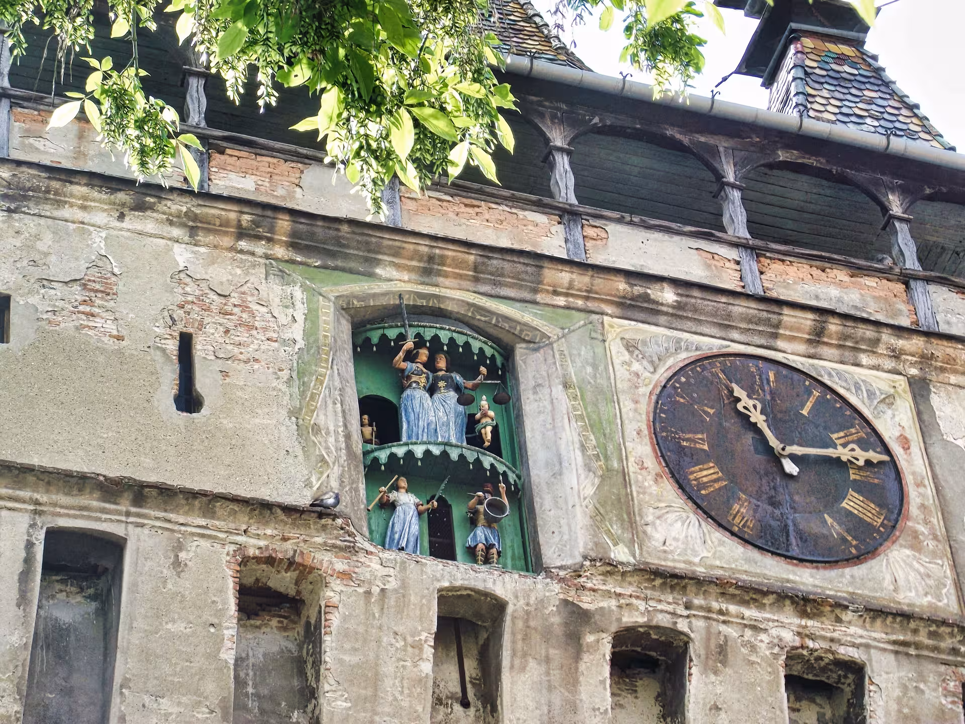 Medieval clock tower with ornate figurines and Roman numeral clock face in Sighisoara, Romania