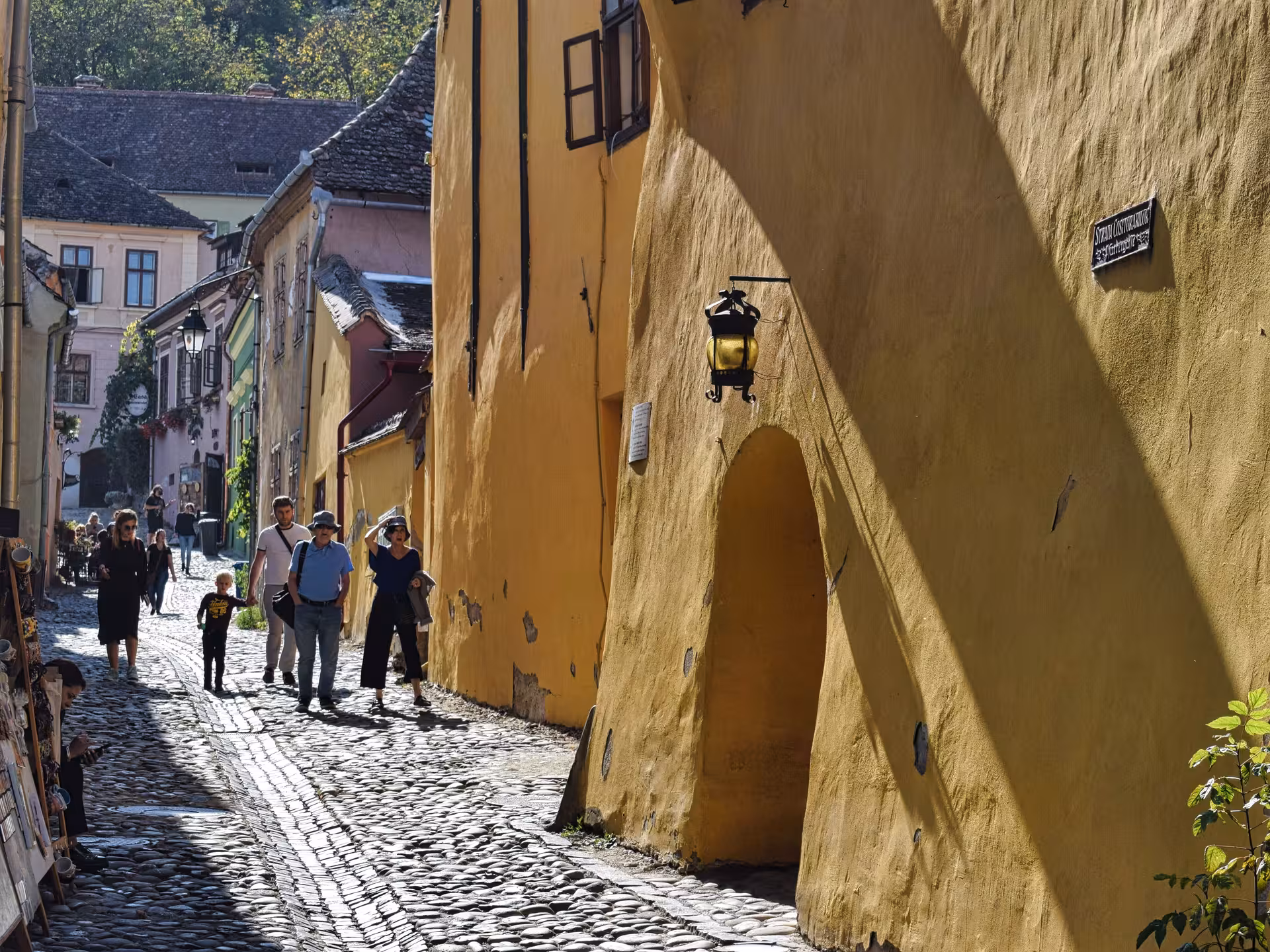 Tourists strolling along a sunny cobblestone street in Sighisoara medieval Saxon town Transylvania Romania