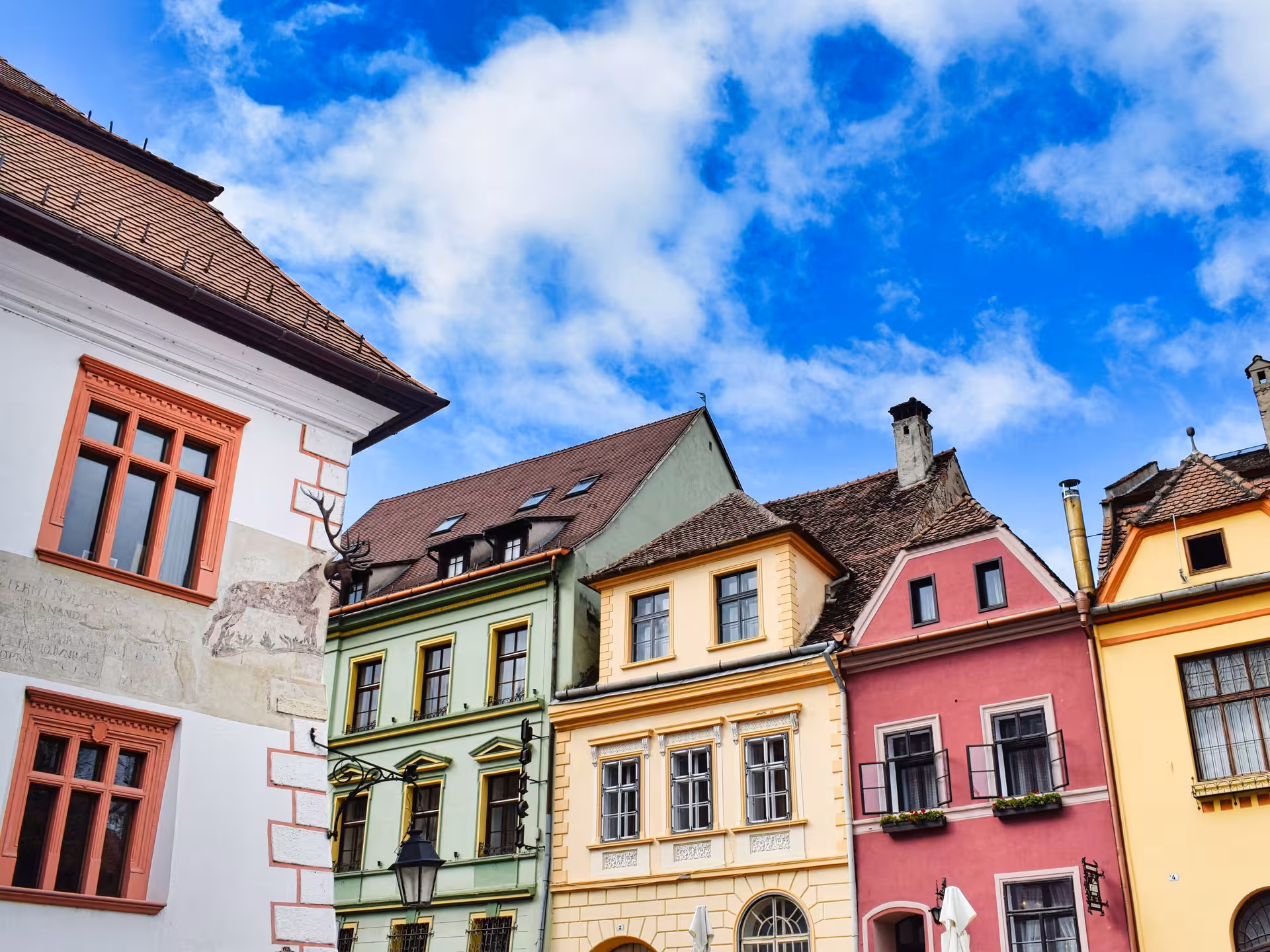 Colorful historic buildings in Sighisoara old town square under blue sky