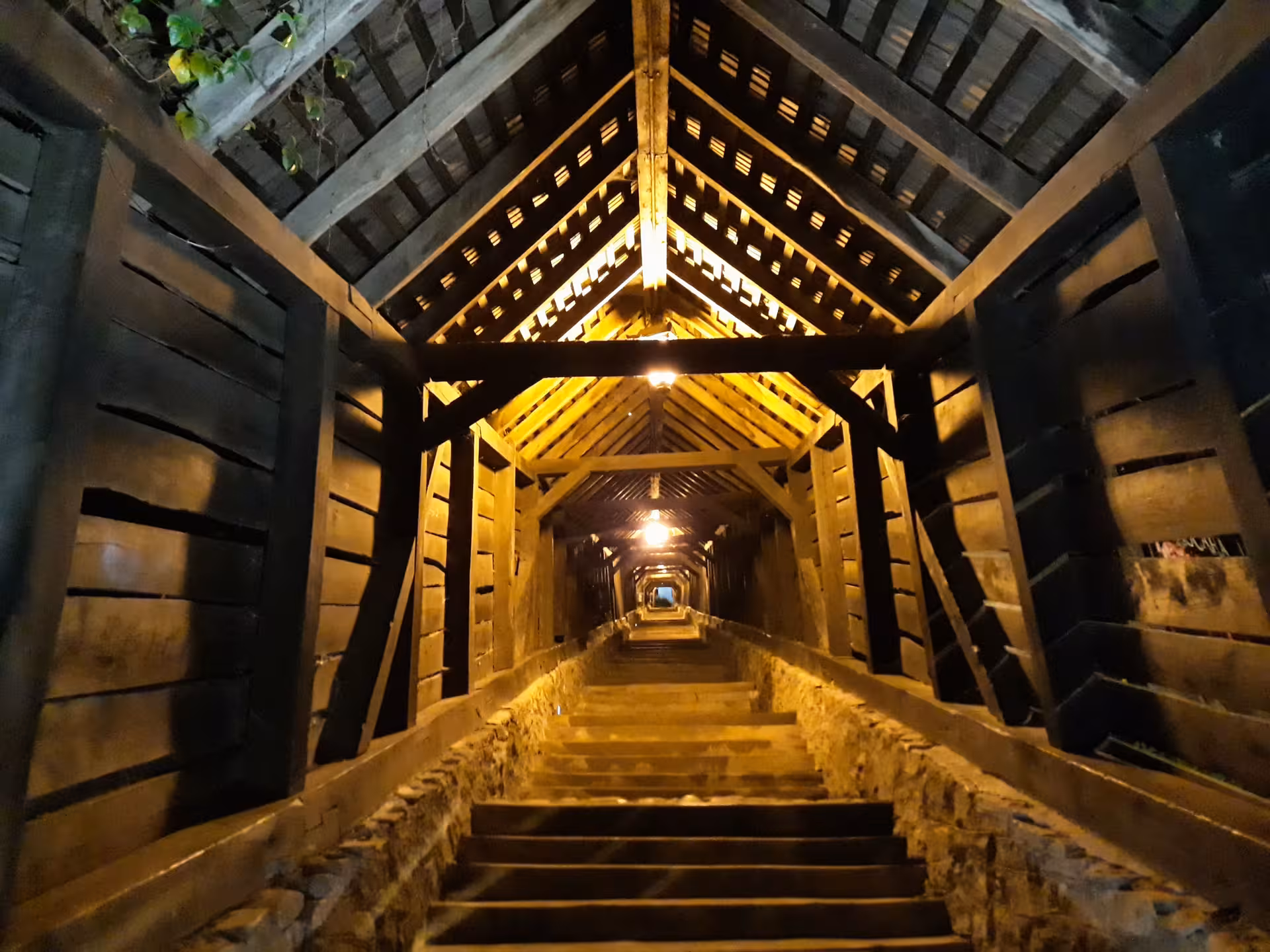 Illuminated covered wooden staircase passage leading to Sighisoara old town citadel at night