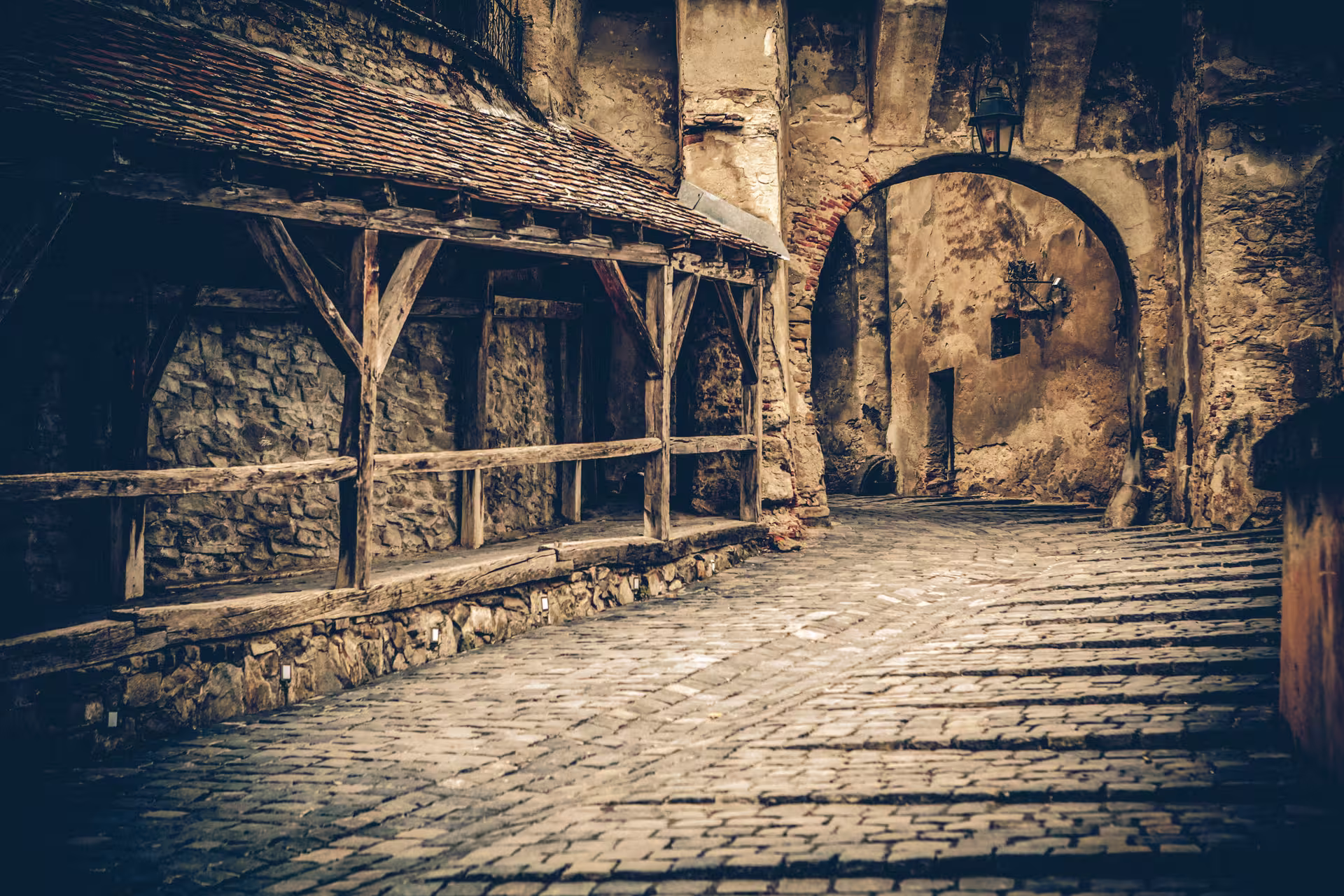 Atmospheric cobblestone alleyway in Sighisoara with rustic arches, ideal for a Dracula-themed candlelight tour experience.