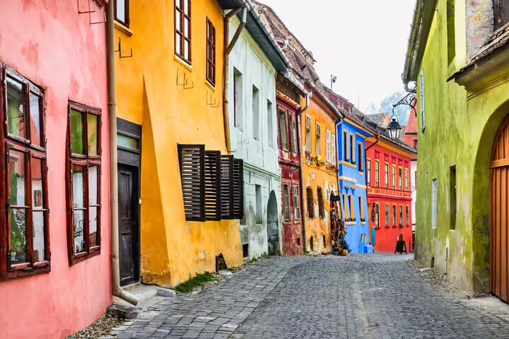 Colorful medieval cobblestone street lined with vibrant painted buildings in Sighisoara fortress old town