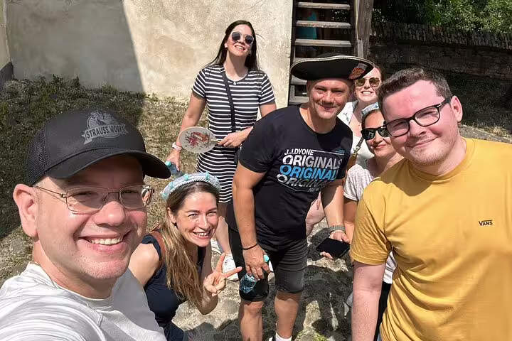 Group of smiling tourists taking a selfie during Sighisoara walking tour adventure on a sunny day