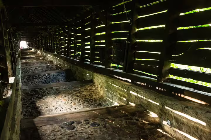 Stone cobblestone corridor with wooden slatted walls letting in streaks of sunlight in Sighisoara fortress