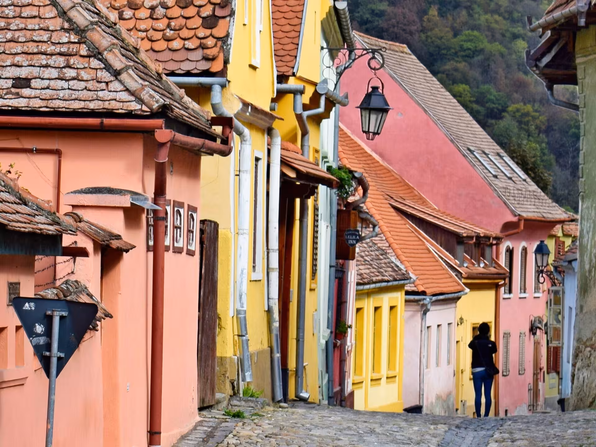 Colorful medieval cobblestone street in Sighisoara old town with a lone walker among historic buildings