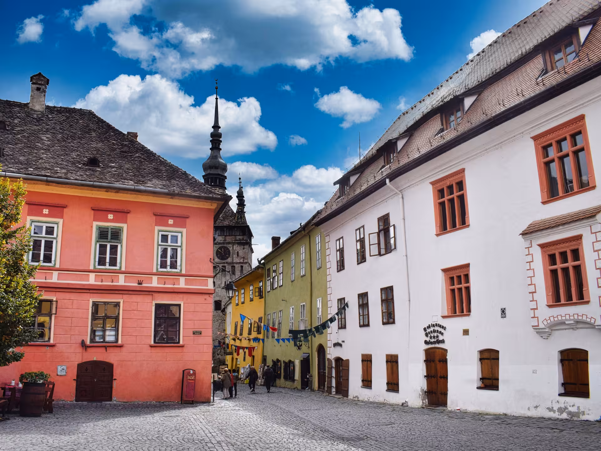 Colorful medieval buildings and clock tower on cobblestone square in Sighisoara old town, Romania