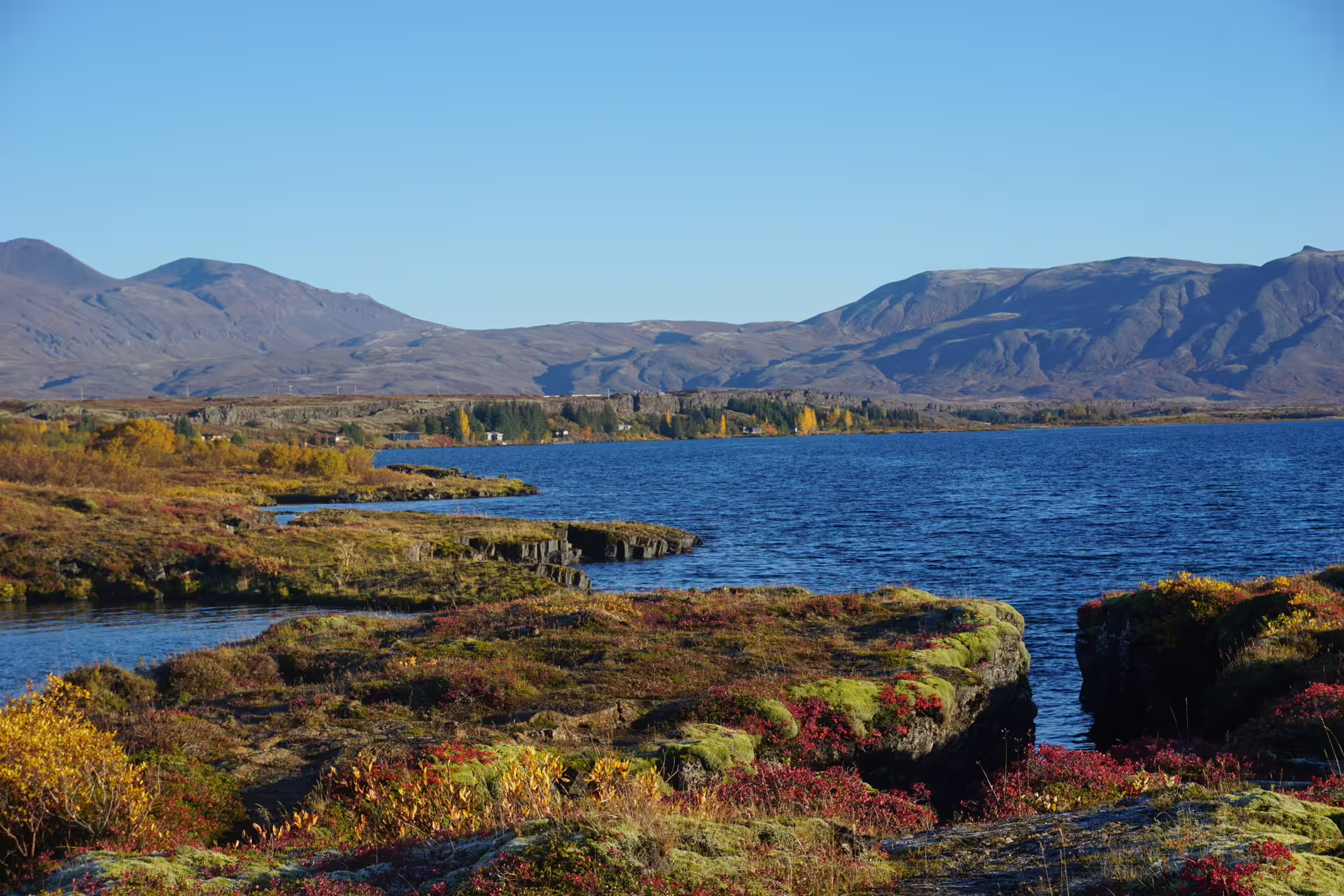 Scenic view of Silfra fissure in Thingvellir National Park, Iceland, with clear blue waters and rugged volcanic landscape.