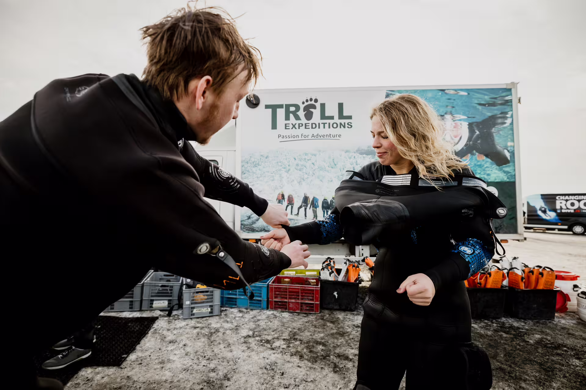 Troll Expeditions guide helping woman put on drysuit for snorkeling tour at Silfra Iceland