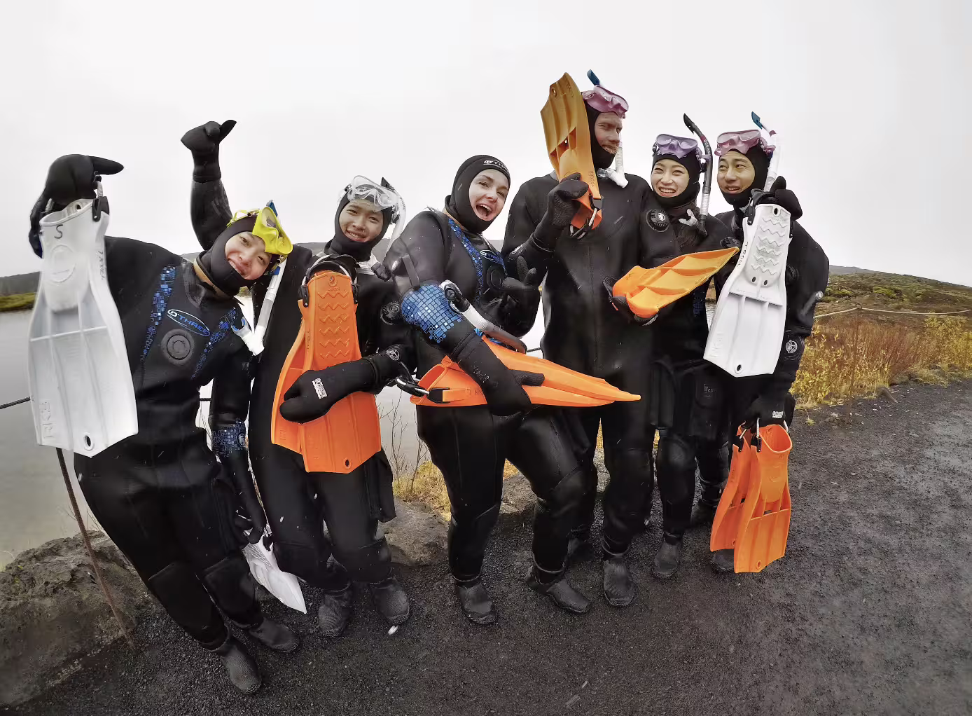 Group of six snorkelers in wetsuits holding fins at Silfra, Thingvellir, Iceland