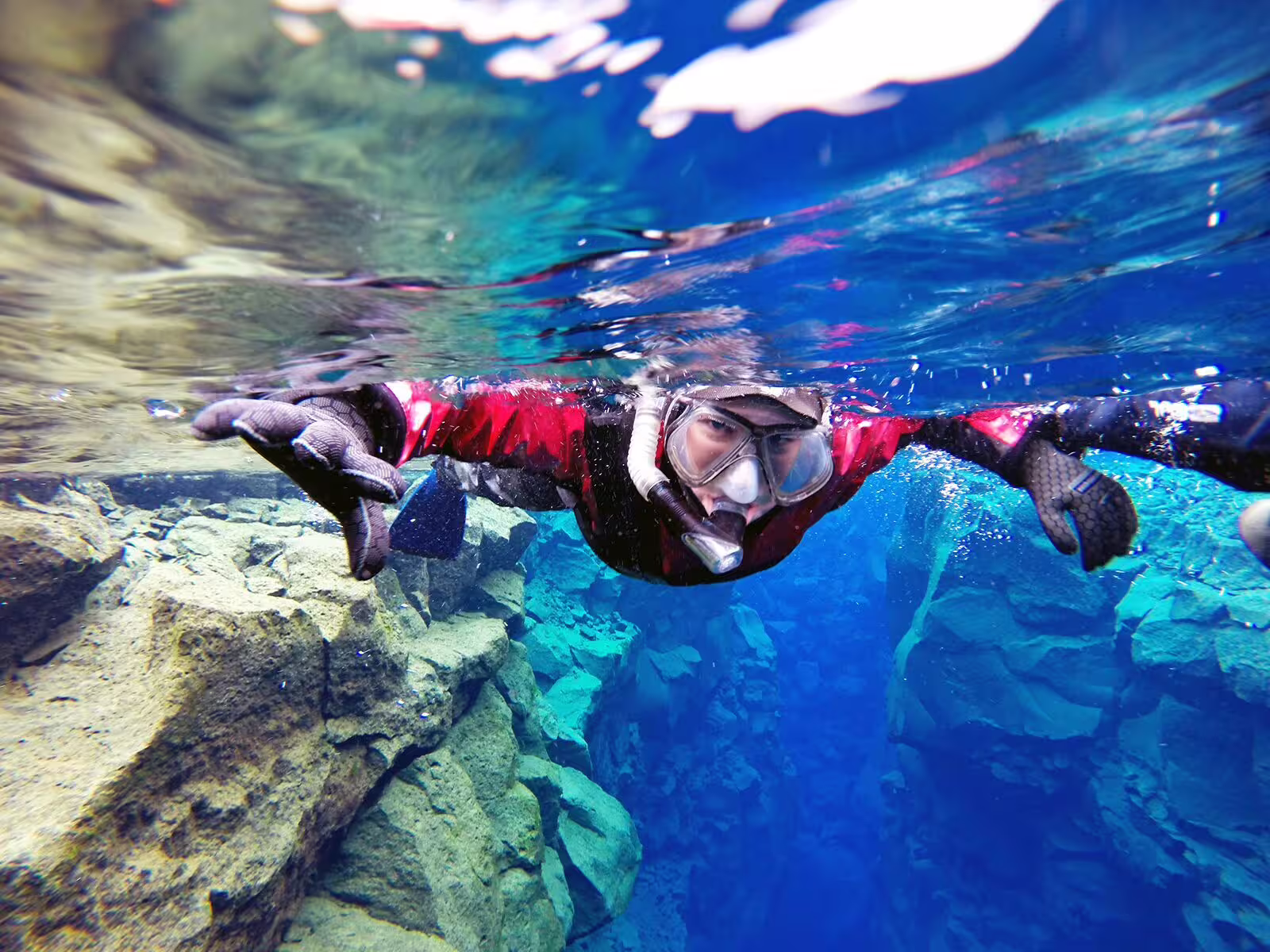 Person snorkeling in Silfra's crystal-clear waters between tectonic plates, offering an unforgettable Icelandic adventure experience.