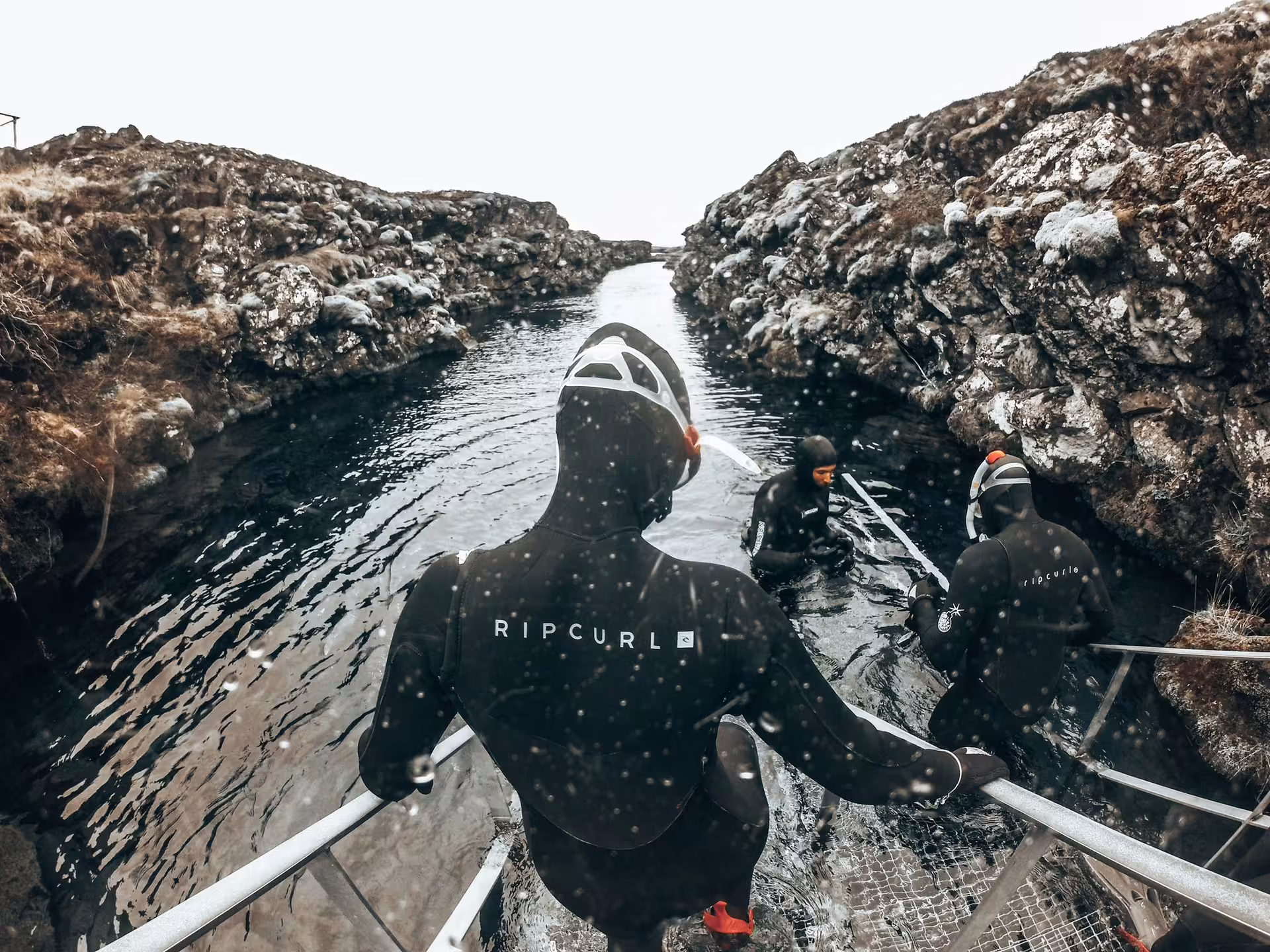 Adventurers in wetsuits prepare to snorkel in Silfra's crystal-clear waters between tectonic plates in Iceland.
