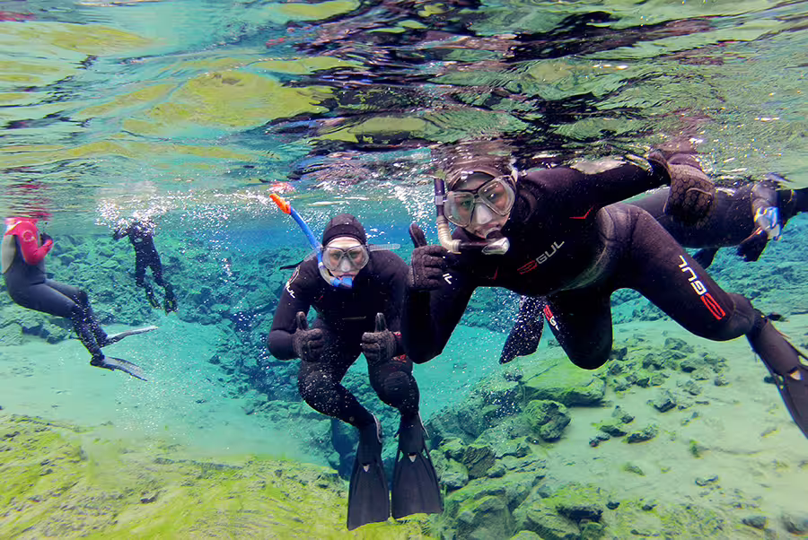Snorkelers explore the crystal-clear waters of Silfra Fissure in Iceland, showcasing the unique underwater experience of snorkeling between tectonic plates.