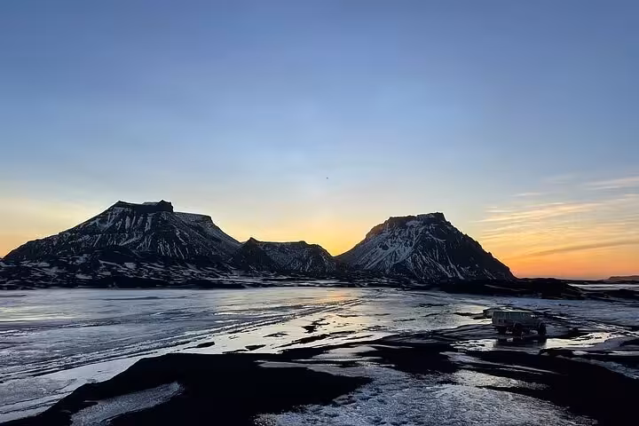 Snow-capped twin mountains at sunset reflected on icy terrain near Reykjavik, Silver Circle tour