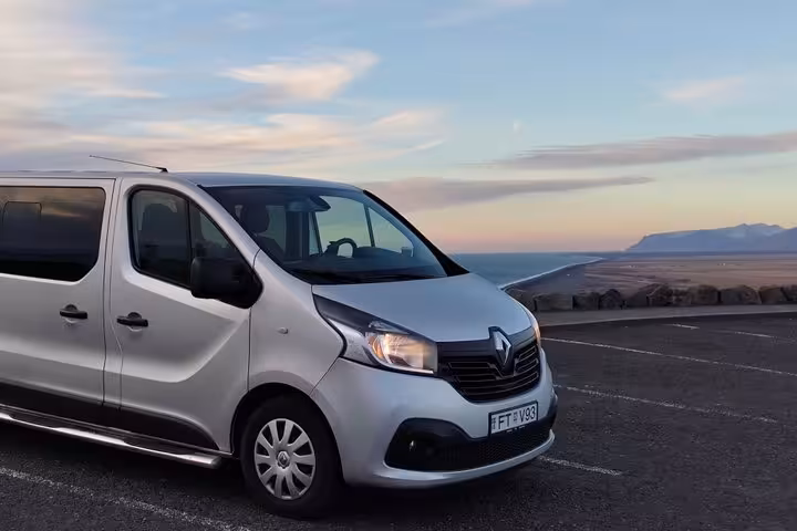 Silver Renault Trafic minivan parked near Keflavik Airport with coastal scenery at dusk