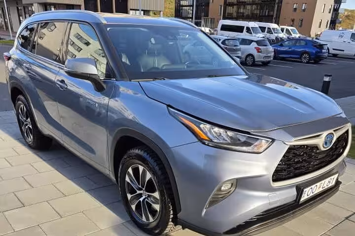 Silver Toyota Highlander Hybrid SUV parked outside modern building in Iceland