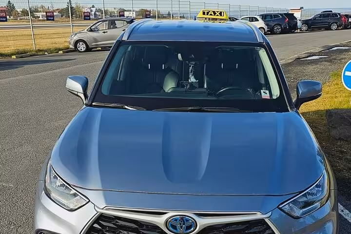 Silver Toyota hybrid taxi SUV with yellow taxi sign on roof parked at airport