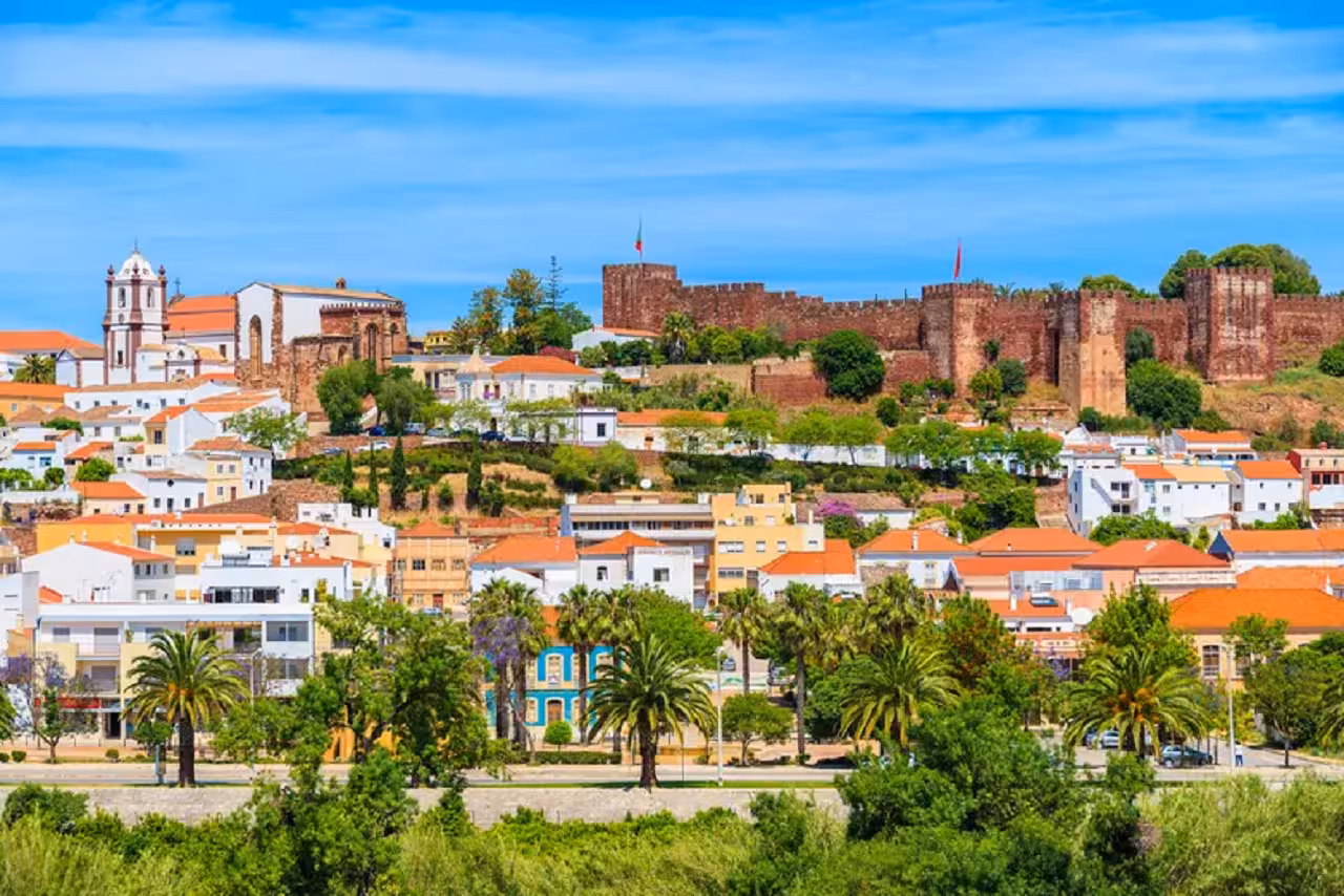 Colorful Silves town beneath its red-brick Moorish castle and palm trees, featured on the Full Day Guided Tour Historical Algarve.