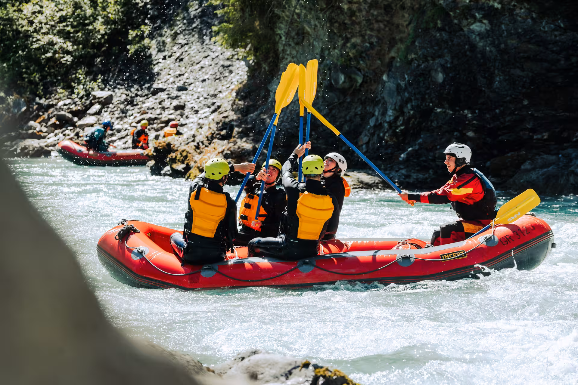 Thrilled rafters celebrating teamwork on a vibrant red raft during an exciting Simme River adventure.