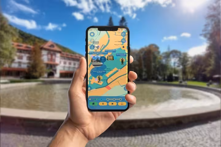 Hand holding smartphone displaying interactive map of Sinaia walking tour with royal palace landmarks