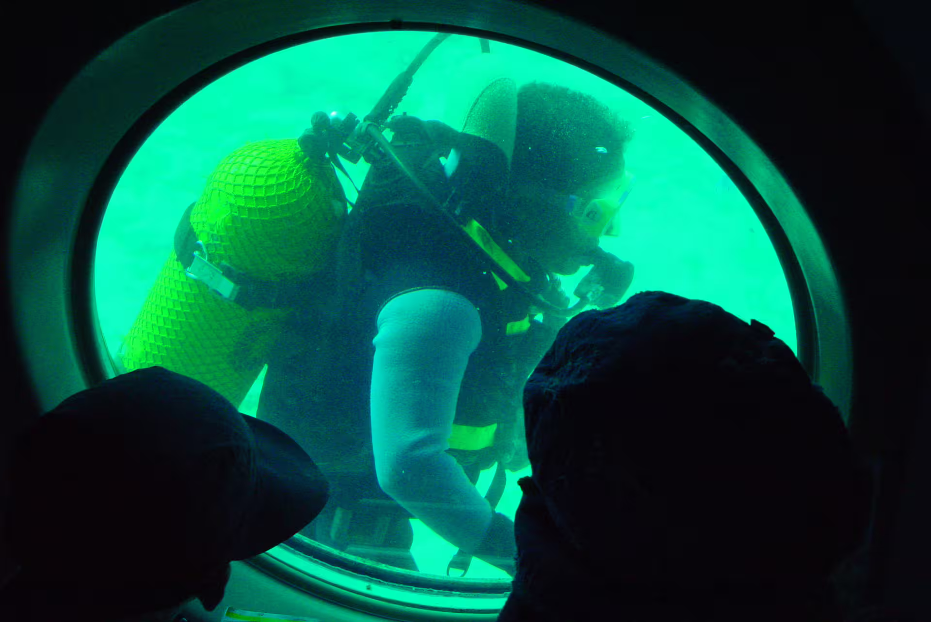 Scuba diver seen through Sindbad Submarine porthole during Red Sea reef viewing tour in Hurghada, Egypt