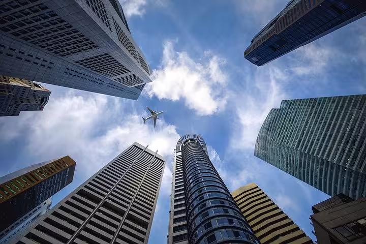 Low-angle view of Singapore CBD skyscrapers with plane overhead on 8-hour private minibus tour