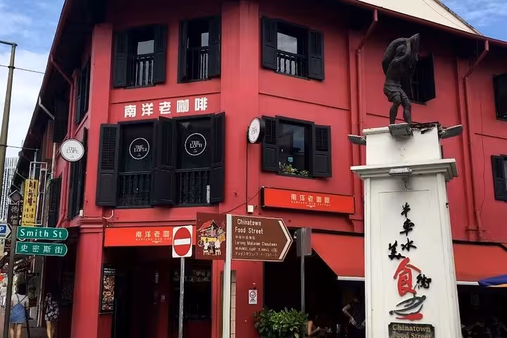 Vibrant red shophouse in Singapore's Chinatown featuring traditional architecture and lively street signs.