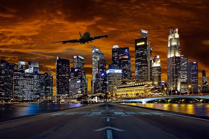 Singapore city skyline glowing at night with plane flying over Marina Bay on private driver tour