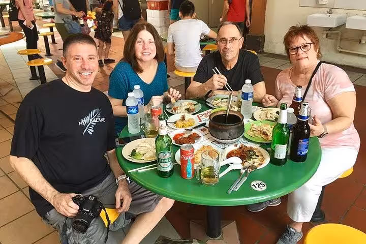 Group enjoying authentic Singaporean street food at a lively hawker center, part of the UNESCO Cultural Experience tour.