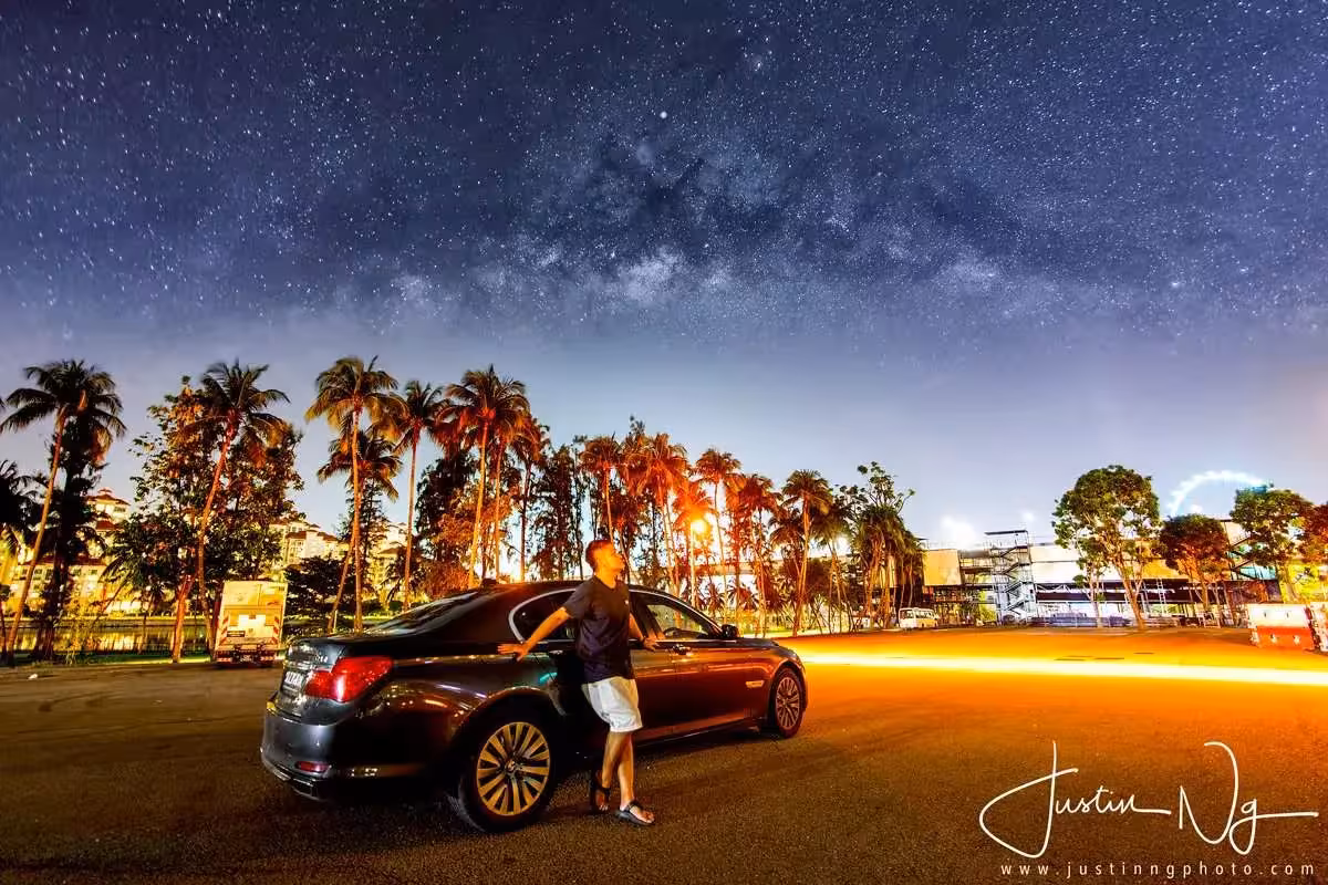 Person stargazing next to a car under a spectacular Milky Way sky in Singapore night photography workshop.
