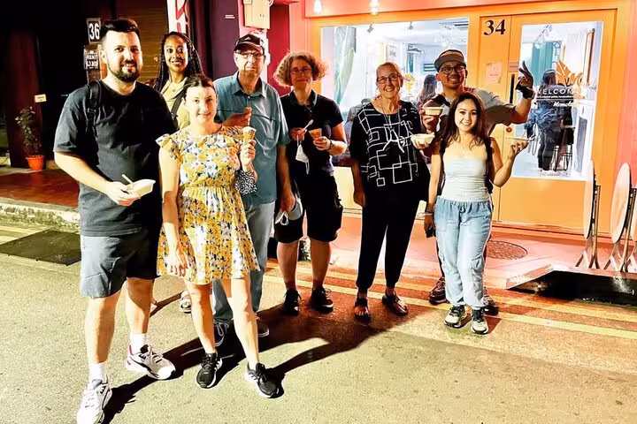 Group of tourists enjoying local street food on a Singapore cultural experience tour.