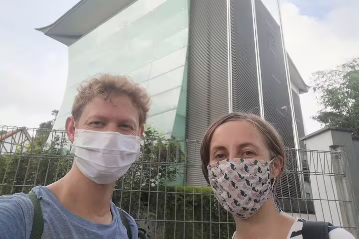 Two tourists wearing face masks on a Singapore self-guided walking tour near a modern glass building