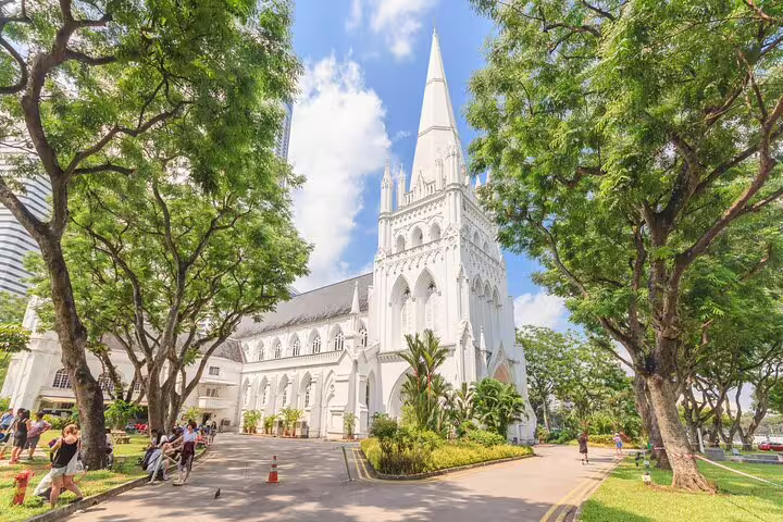White gothic St Andrew's Cathedral surrounded by lush trees in Singapore city center