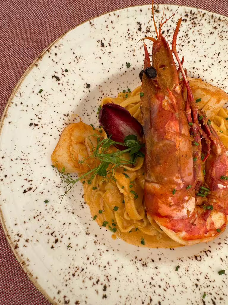 Gourmet pasta dish with large prawn, showcasing local culinary delights on the Sintra & Cabo da Roca private van tour.