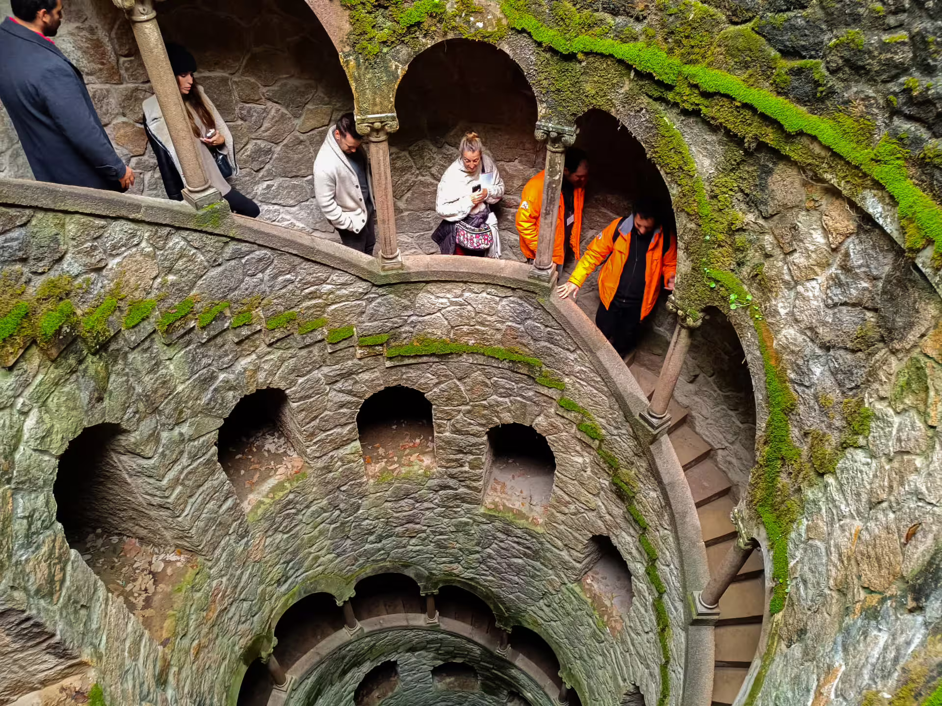Visitors explore the mystical spiral staircase of the Initiation Well at Quinta da Regaleira on a Cabo da Roca tour.