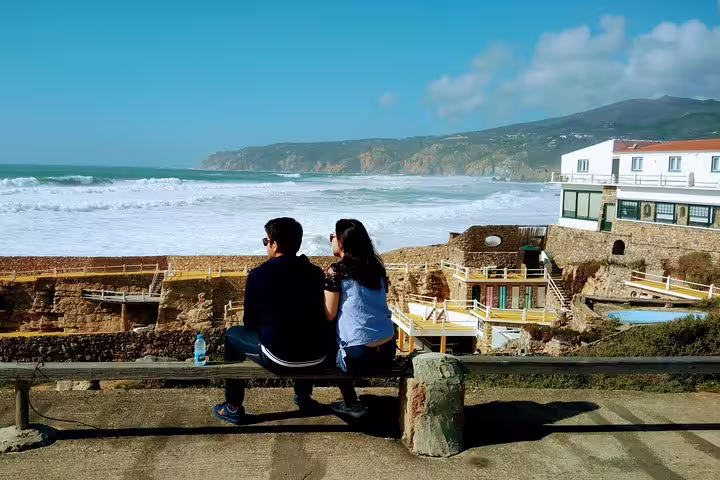 Couple enjoying ocean views from a scenic spot on the Sintra and Cascais Village Tour, highlighting coastal beauty and heritage sites.