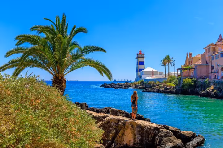 Discover the scenic beauty of a coastal lighthouse view with palm trees and vibrant waters in Sintra's charming landscape.