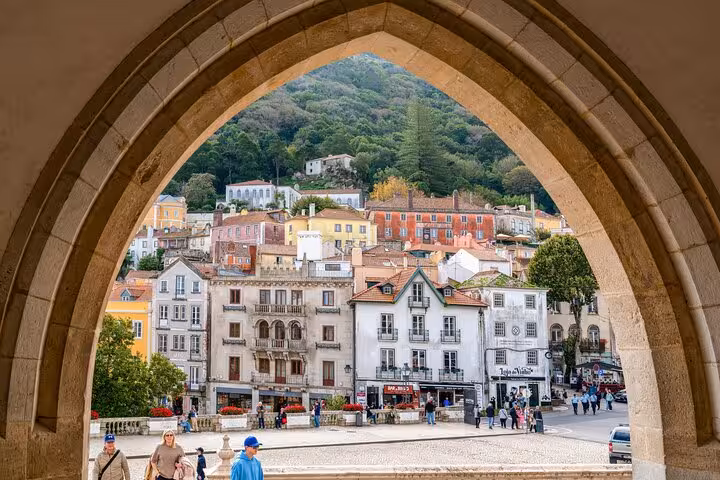 Charming view of Sintra's colorful townhouses through an arched window, highlighting the town's historic charm.