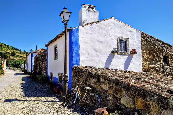 Charming cobblestone street in a picturesque village with traditional white and blue houses, part of Sintra Dream Villages Tour.