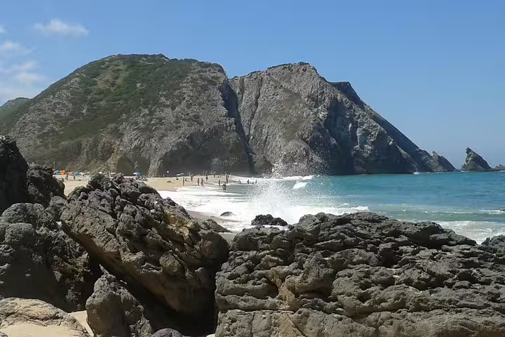 Scenic view of Praia da Adraga beach with dramatic cliffs and turquoise waves, featured in Sintra's Dream Villages Tour.