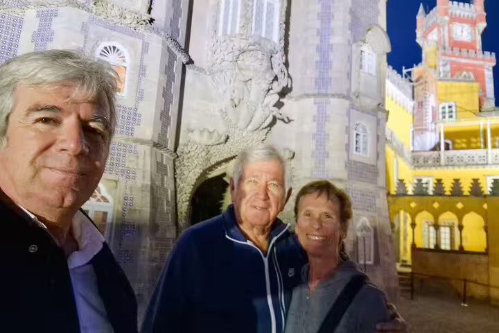 Visitors enjoying a private tour of Sintra's iconic monuments from Lisbon, with the stunning architecture illuminated at night.