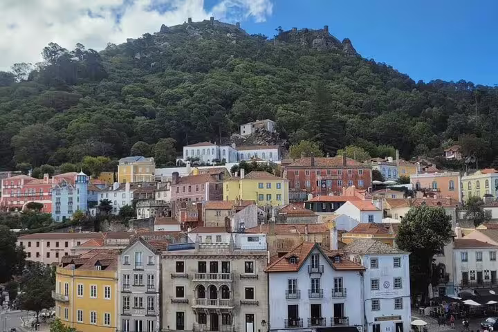 Colorful hillside village in Sintra, Portugal, with lush greenery and the historic Moorish Castle atop the scenic mountain.