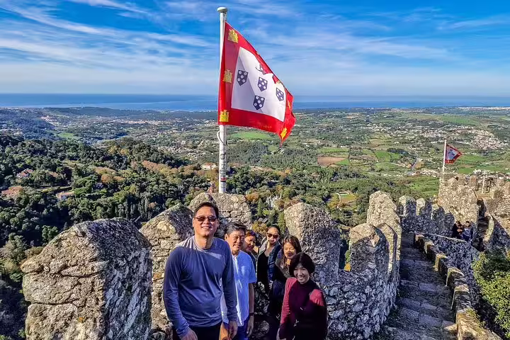 Tourists enjoying panoramic views from the historic Moorish Castle in Sintra during a private tour with monument tickets from Lisbon.