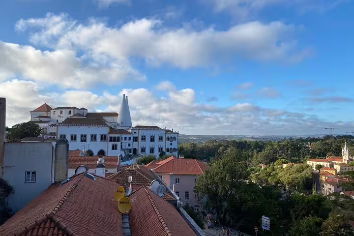 Panoramic view of Sintra with the National Palace, surrounded by lush greenery under a vibrant blue sky.