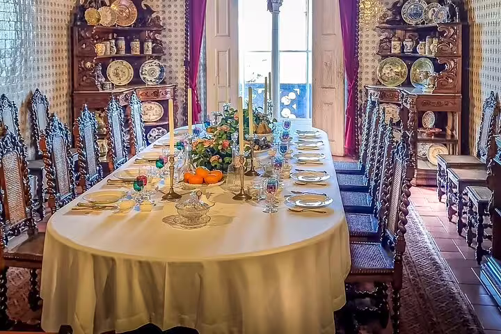 Ornate dining room in a Sintra palace, featuring an elegantly set table with vintage decor, part of a private tour from Lisbon.