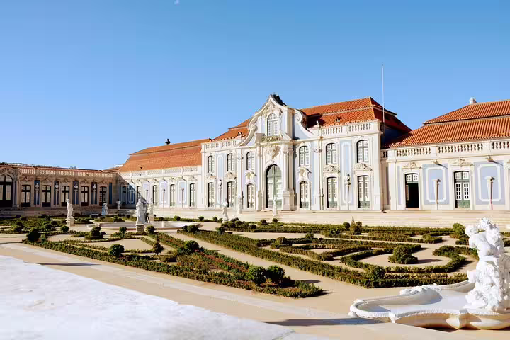 Elegant palace facade with manicured gardens under blue skies, featured in Sintra World Heritage and Cascais Village Luxury Tour.