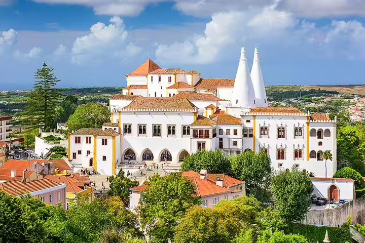 Aerial view of Sintra National Palace with its iconic chimneys, surrounded by lush greenery on a day trip from Lisbon.