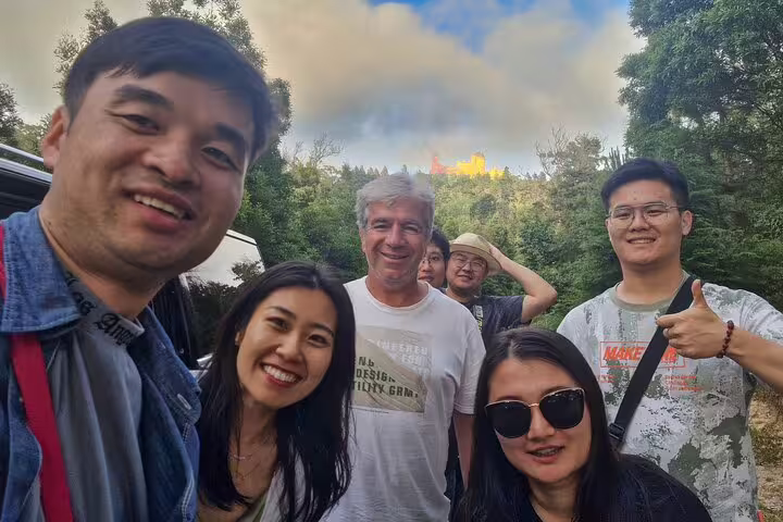 Group of tourists enjoying a scenic moment with Pena Palace in the background during a Sintra, Roca, and Cascais private tour.