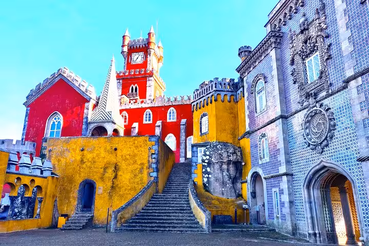 Vibrant view of Sintra's Pena Palace with its colorful towers and intricate architecture under a clear blue sky.